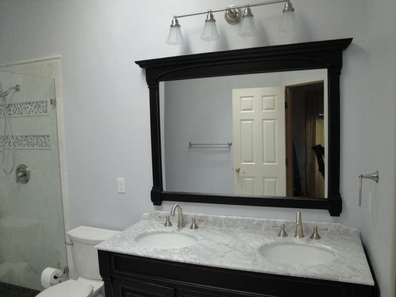 Dark-framed mirror and vanity in the white marble bathroom