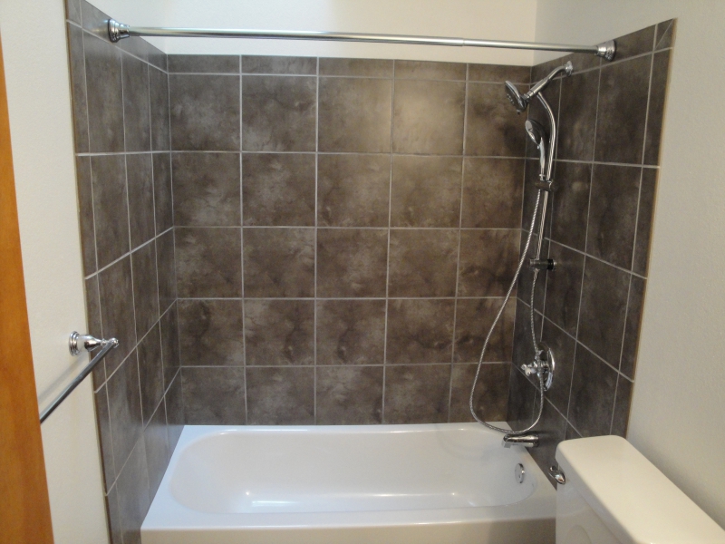 White bathtub with a grey tile shower enclosure