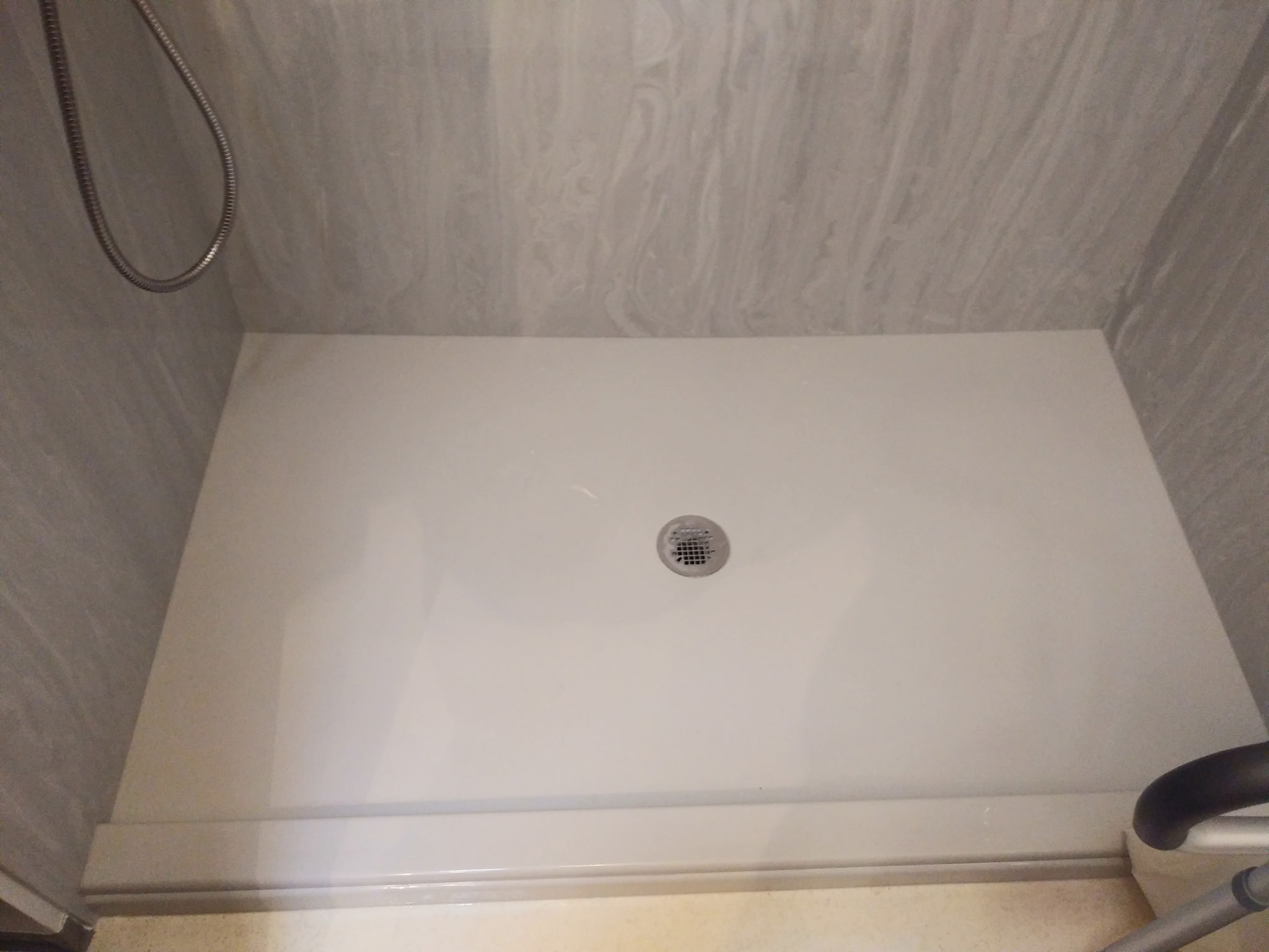 White shower base with a round drain and a visible raised lip at the entry